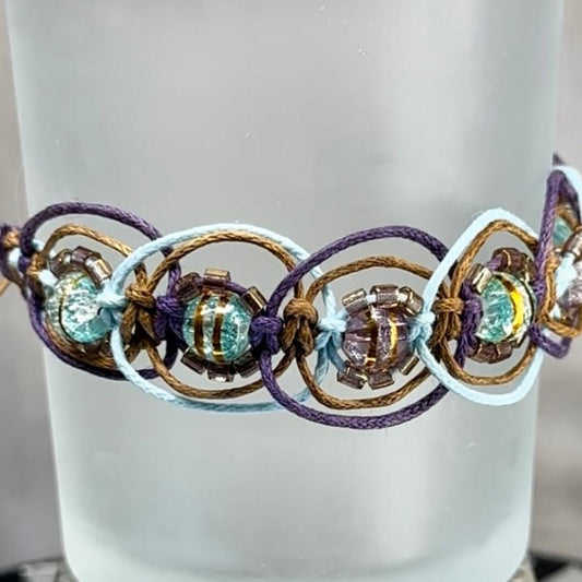 Woven bracelet featuring translucent teal and purple beads