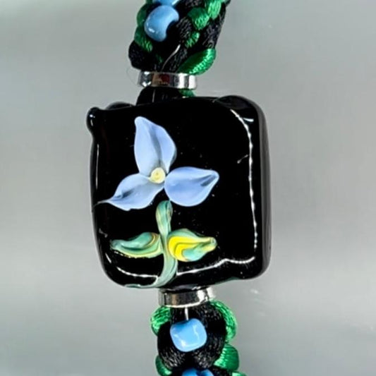 Blue flower on black and green cord with sky blue seed beads